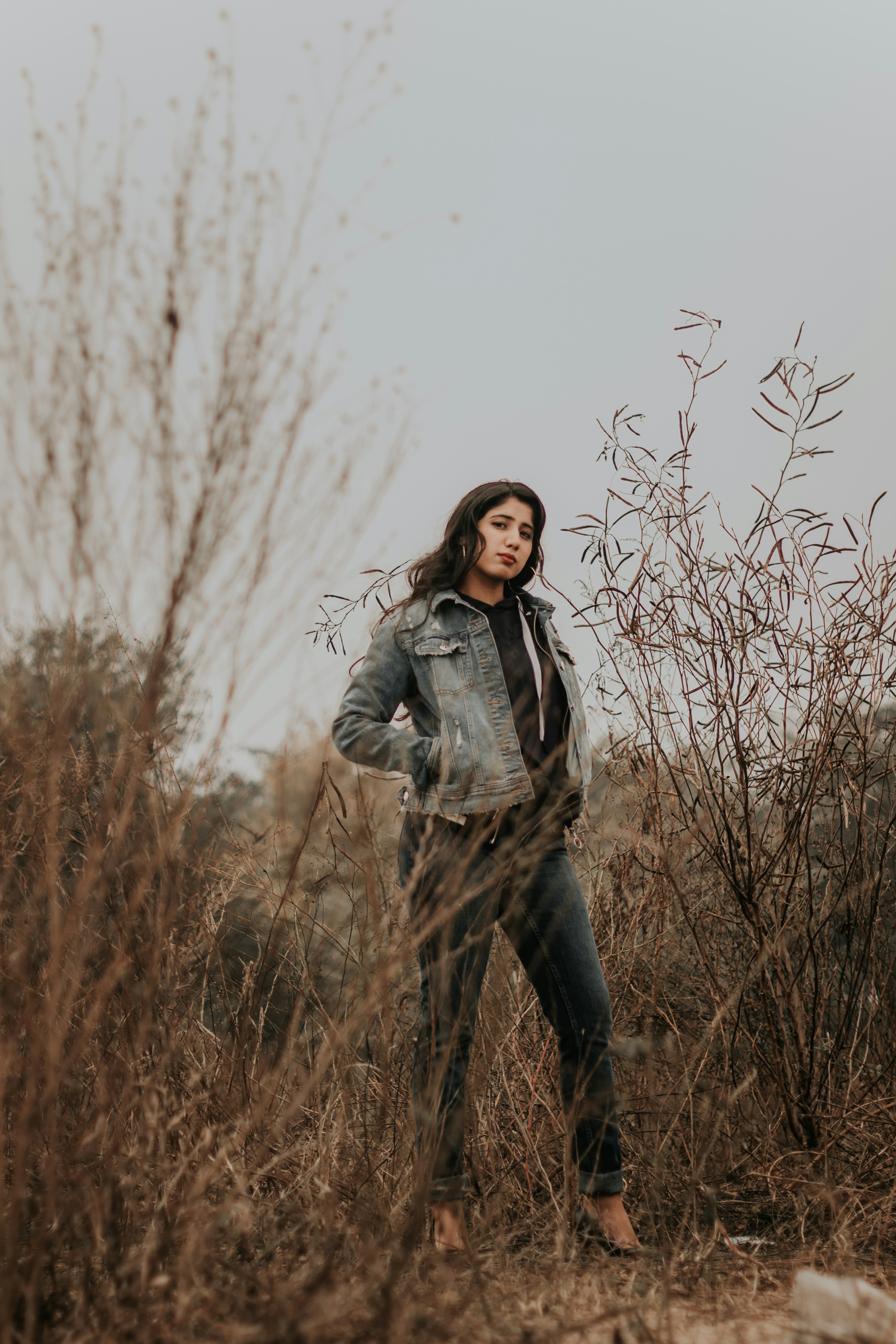 woman in gray jacket standing on brown grass field during daytime